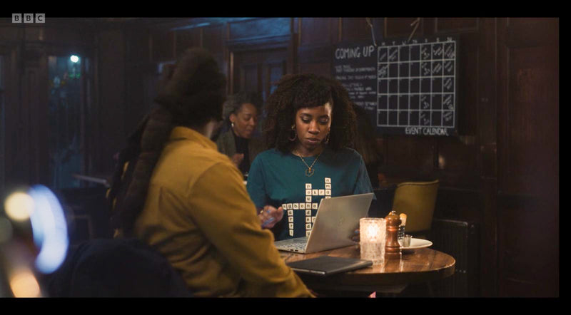 Two women sitting at a table with a laptop in a dimly lit room.