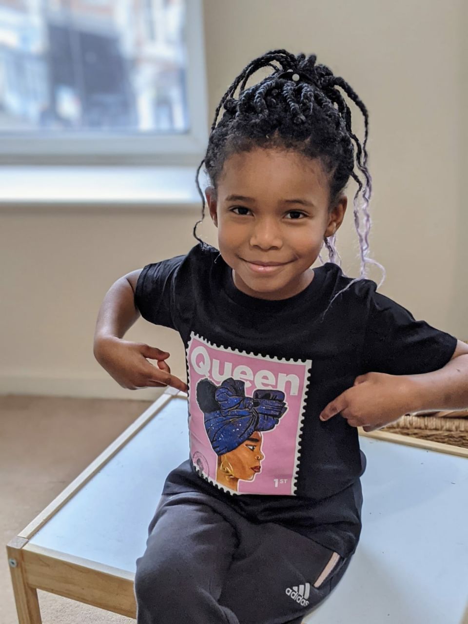 A girl wearing a t-shirt, with the depiction of a black queen on a stamp
